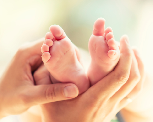 a woman's hands wrapped around her baby's feet